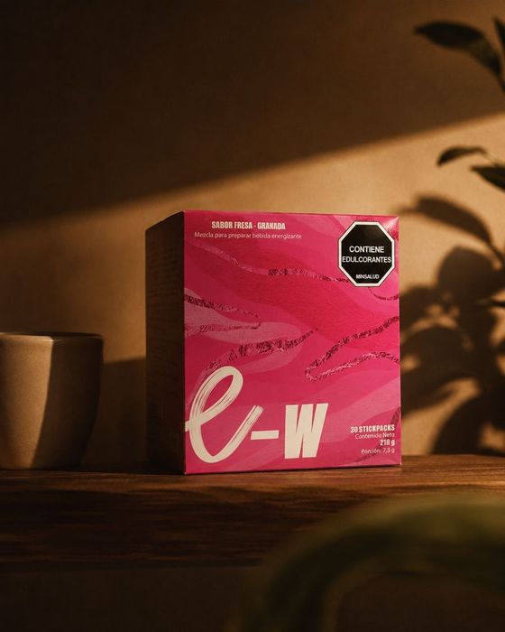 علبة e-W على رف خشبي بجانب كوب في ضوء المساء